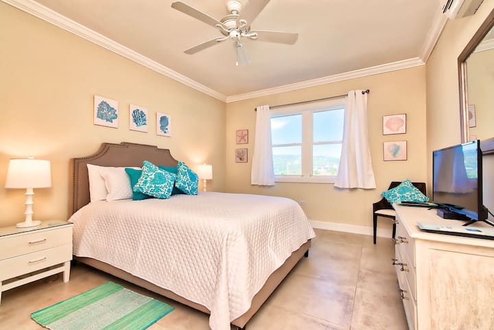 غرفة نوم مفروشة استوائية بسرير كوين مع ديكور فيروزي. 