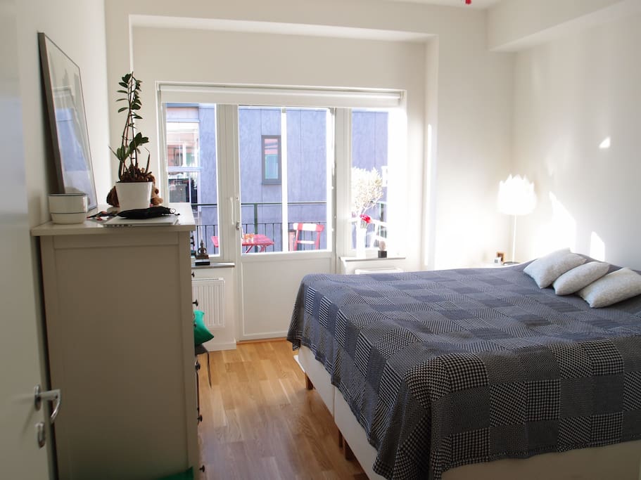 The bedroom with a view towards the balcony and yard.
