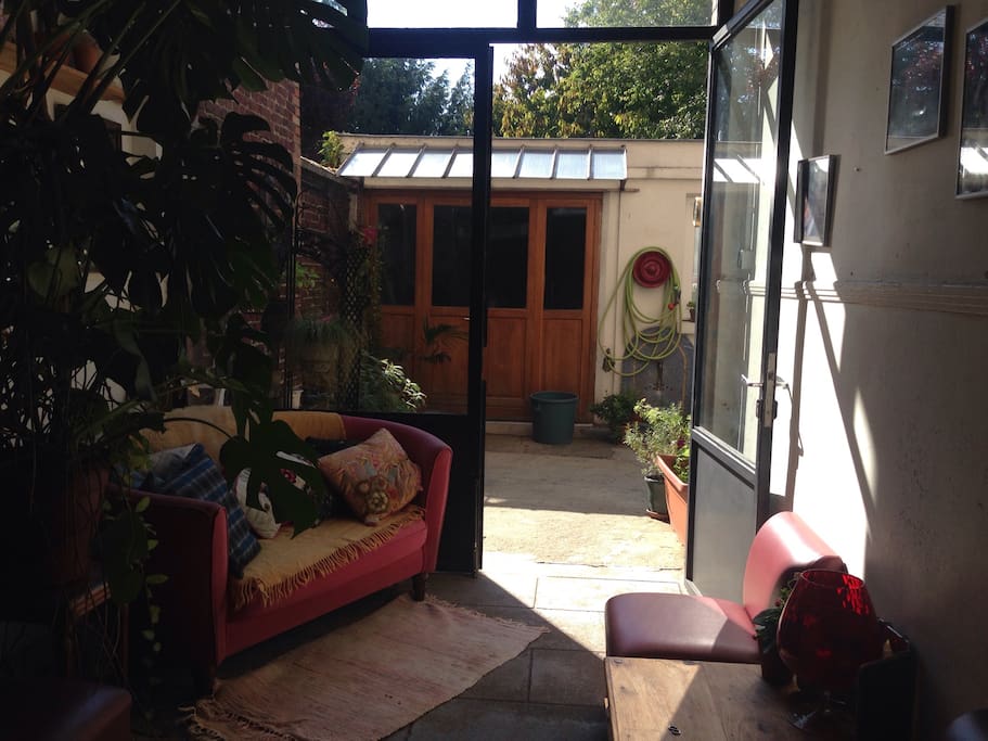 Le portail d'entrée (côté rue) mène directement sous ce porche vitré, lui même menant à la cour puis à la maisonnette. L'entrée de mon logement personnel se trouve également sous ce porche, à droite sur la photo.