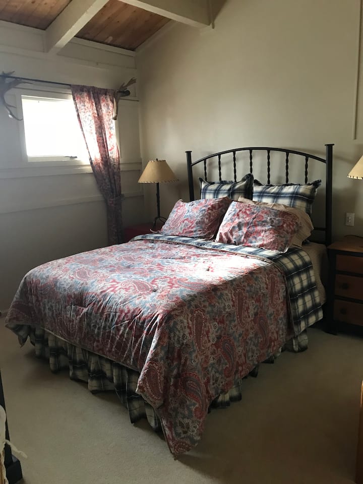 חדר שינה ראשי בקומה העליונה עם חדר רחצה פרטי ומיטת קווין סייז.