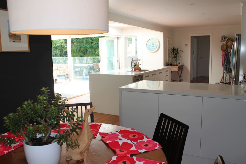 Openplan kitchen/dining with bifold doors overlooking outdoor room, backyard and pool