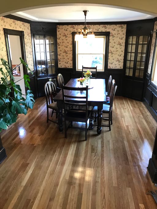 Solid wood dining table for family and group dinners. Seats up to 8 with an additional table and two chairs nearby.