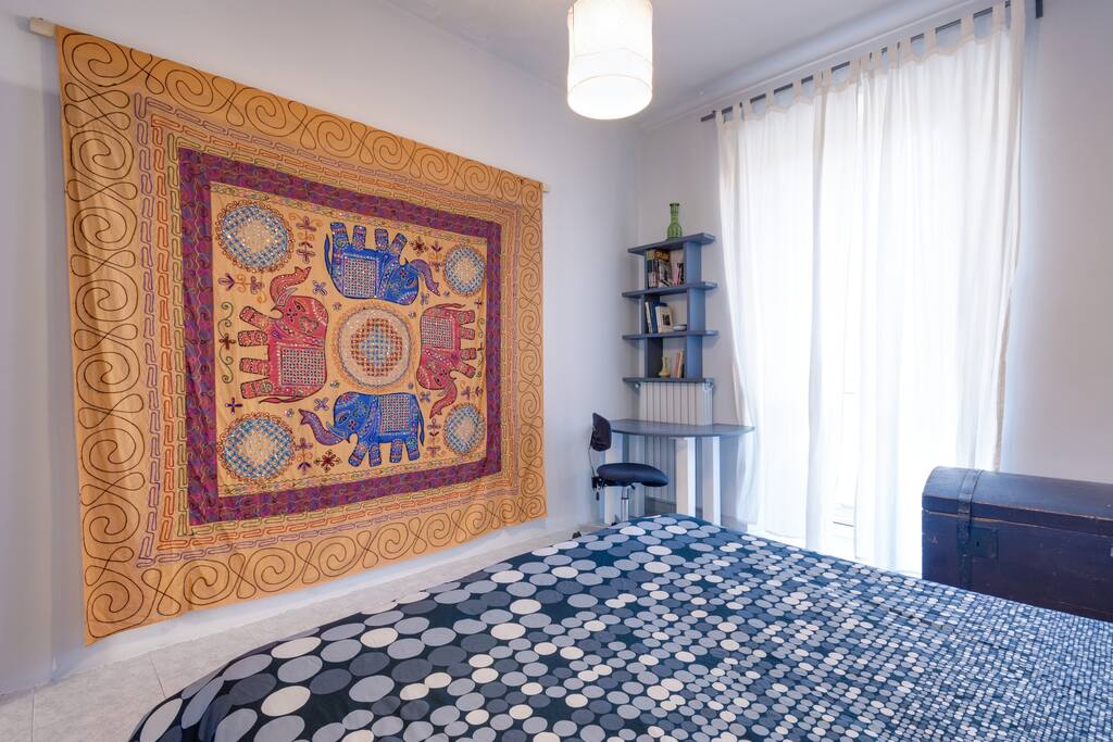 letto, finestra e piccolo scrittoio con libreria