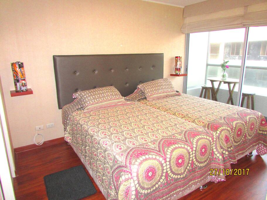 Dormitorio amplio con baño incorporado, walking closet y balcón con mesita y vista al mar.