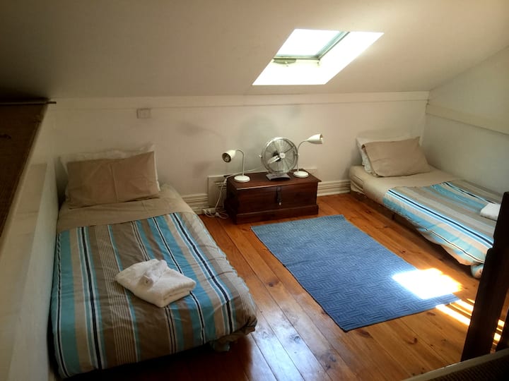 غرفة نوم واحدة في مساحة علوية مثيرة للاهتمام مع مكيف هواء عكسي ولمحات إلى الشاطئ من النافذة.