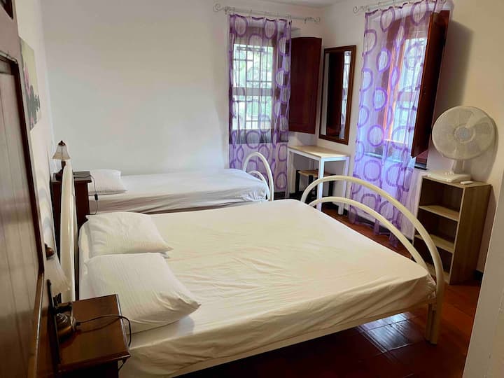 Dormitorio dos con una cama doble, una cama individual y un ventilador con control remoto