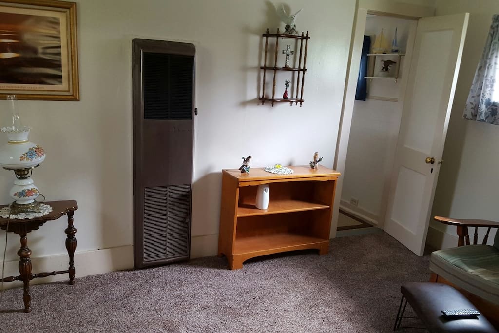 View of the Living room which consists of a futon, recliner, bookshelf, television and an air conditioner. Newly carpeted.