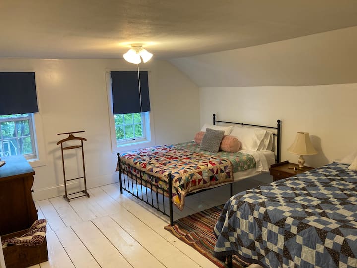 La chambre Nellie à l'étage dispose de deux lits queen confortables et de couettes faites maison pour une nuit de sommeil paisible.