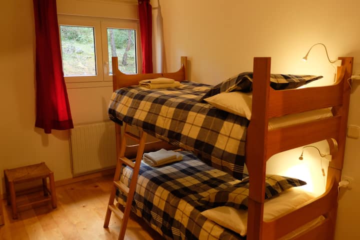 Chambre quadruple avec deux lits superposés et vue sur le jardin