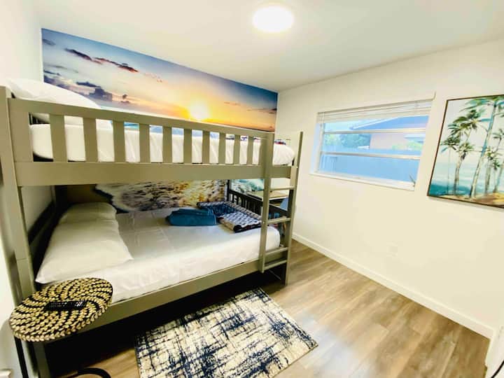 Cama de tamaño completo sobre una litera de tamaño completo con capacidad para 4 personas. Escritorio, luz de escritorio con estación de carga USB y armario para almacenamiento. Smart TV.