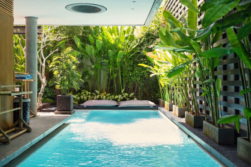 Large private salt water pool with floating bean bags, surrounded by tropical garden. The pool provides both sun and Shade to relax in