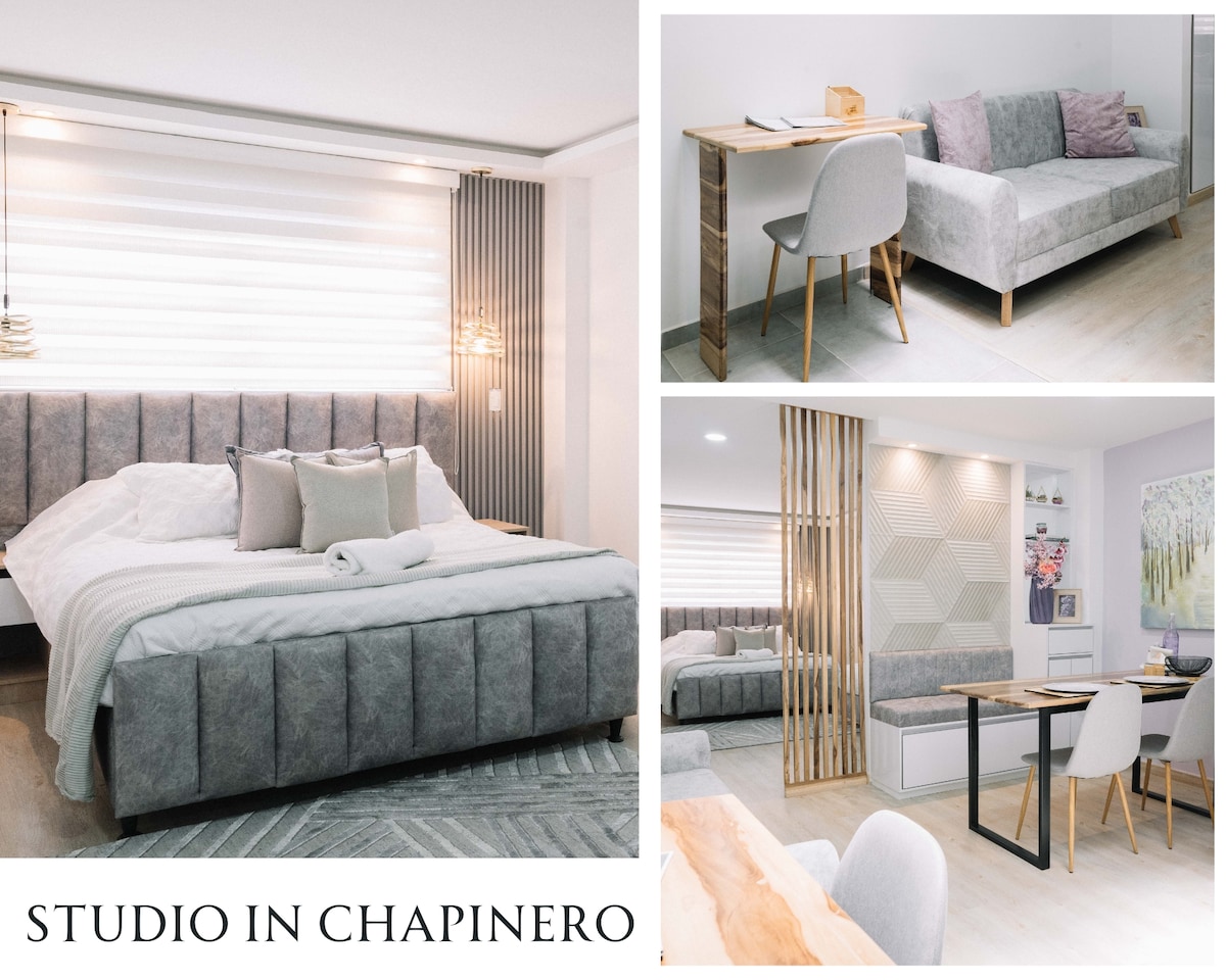 The studio is designed with a spacious queen bed and a comfortable single sofa bed. A small desk is positioned near a window, with a dining table and chairs available for meals. Neutral tones create a calm environment, enhanced by soft lighting.
