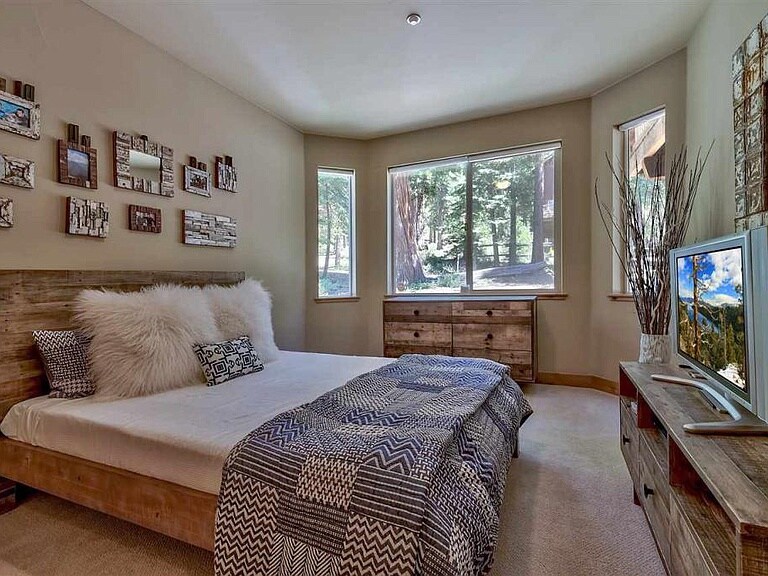 ห้องนอนชั้นล่างพร้อมเตียงควีนไซส์และสมาร์ททีวีจอแบน