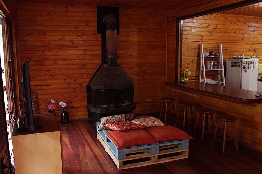 Sala de estar com tv, lareira e cozinha americana.