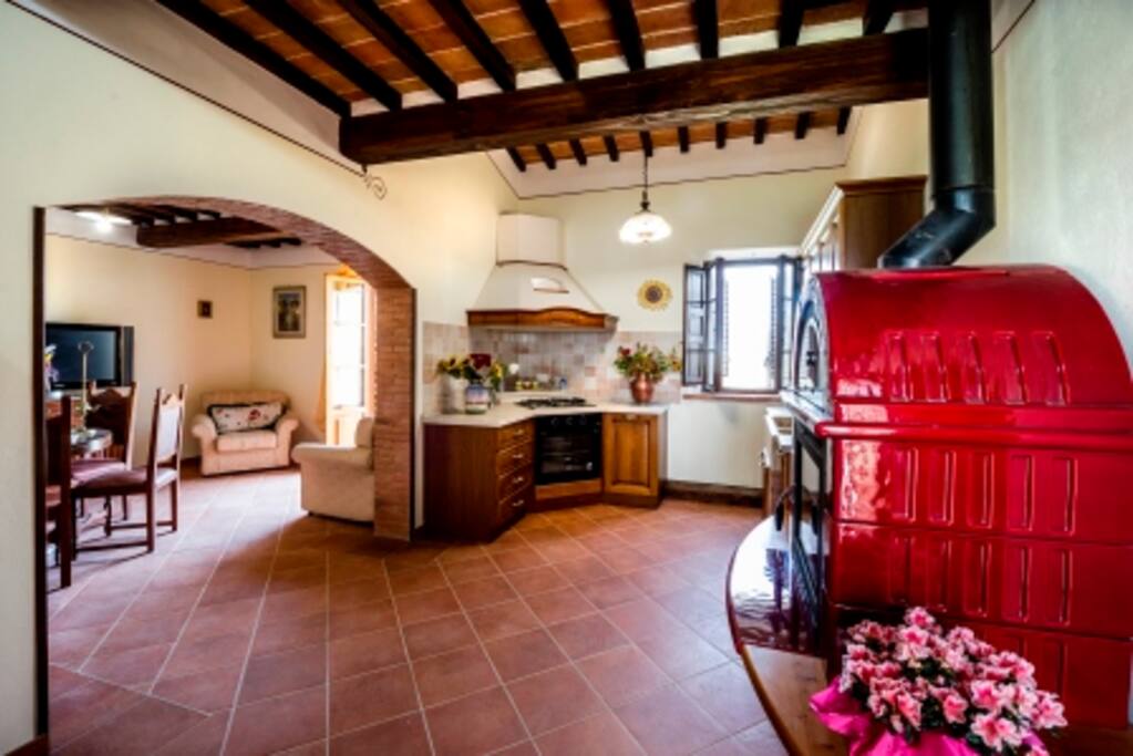 Cucina con stufa e forno a legna, forno elettrico e soggiorno
