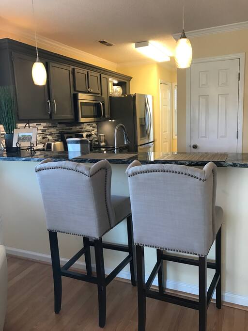 Comfortable upholstered bar stools with granite countertops and high bar.