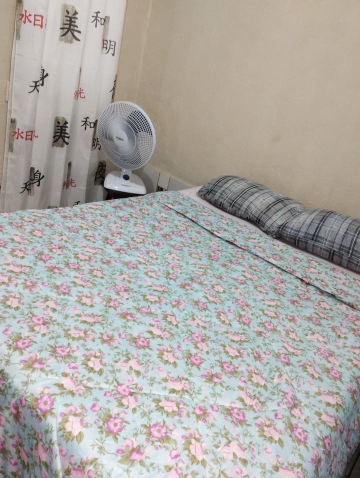 Двойна спалня с спално бельо и вентилатор.