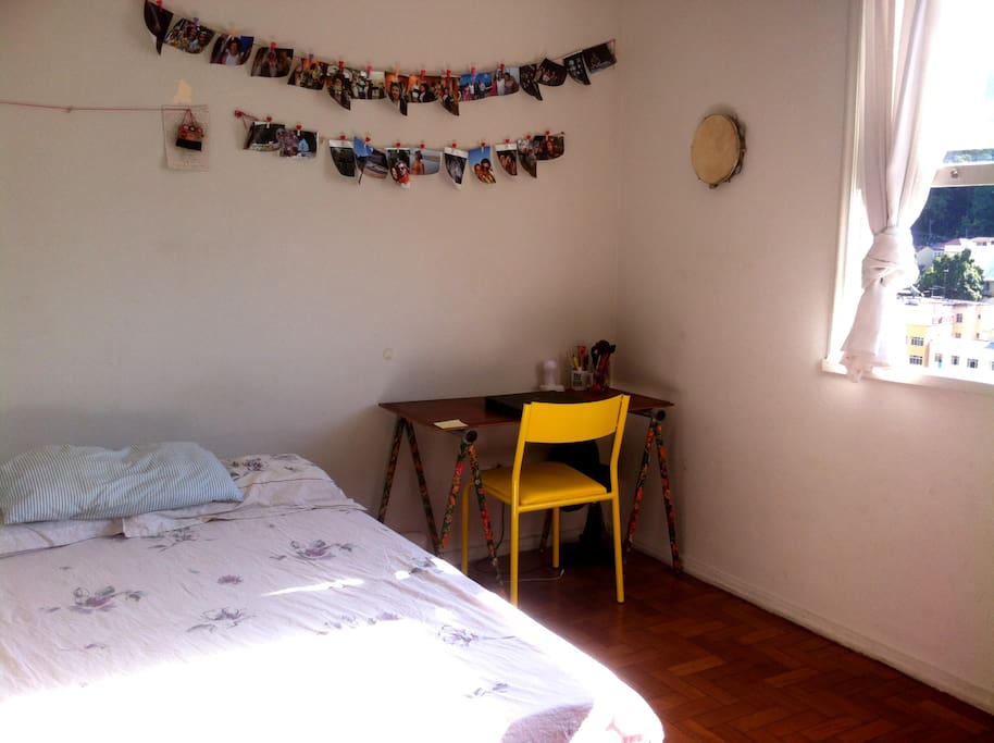 Cama de casal, bancada para computador, quarto com janela.