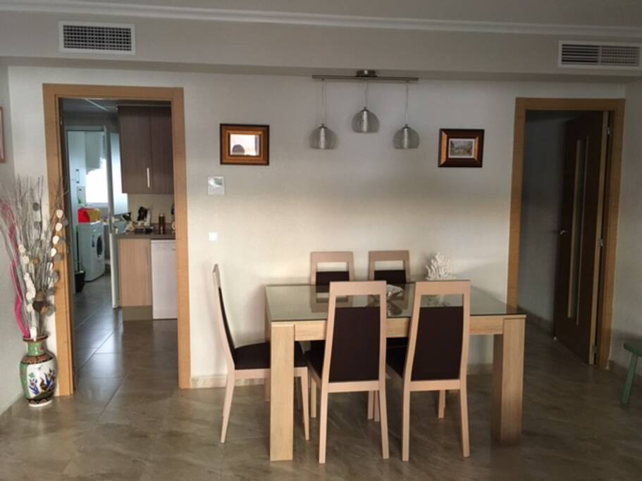 El salón se comunica con la cocina y el pasillo. Mesa con 6 sillas.