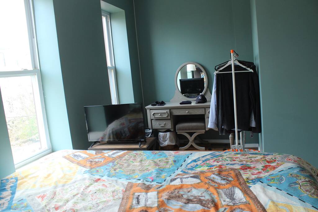 Master bedroom showing vanity and clothes rack, Tv and the oversized space of the room.