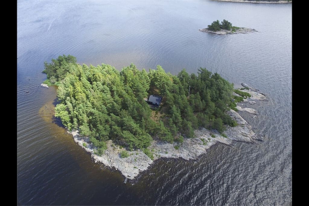Main house embedded in the forest as seen from a western bird eye perspective visualizing the south shore great for recreational activities with it's large and lavishly smooth rocky surfaces great for swimming and sunbathing whilst with ease maintaining visual contact with children >4 years can play supervised along >1/3 of the islands total shoreline.