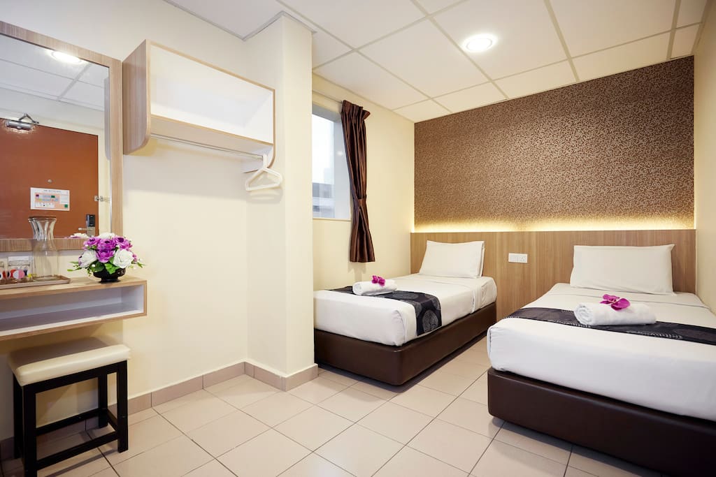 This is our Deluxe Twin Room. It comes with fitted bathroom, shower and WC, flat screen TV, cable TV, air-conditioning, working desk, vanity mirror, free drinking water. Bathroom amenities are provided, hair dryer and ironing facilities are on request.