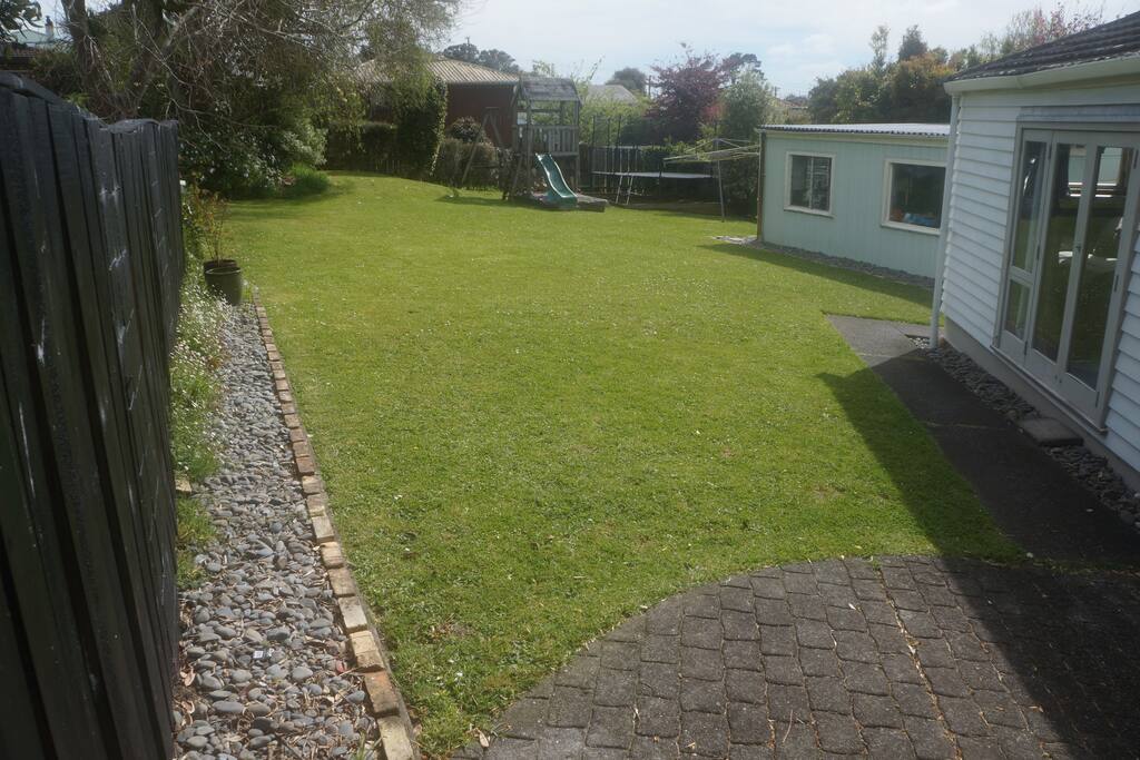 Fully fenced back garden with children's playground, including swings, slide, sandpit and trampoline.