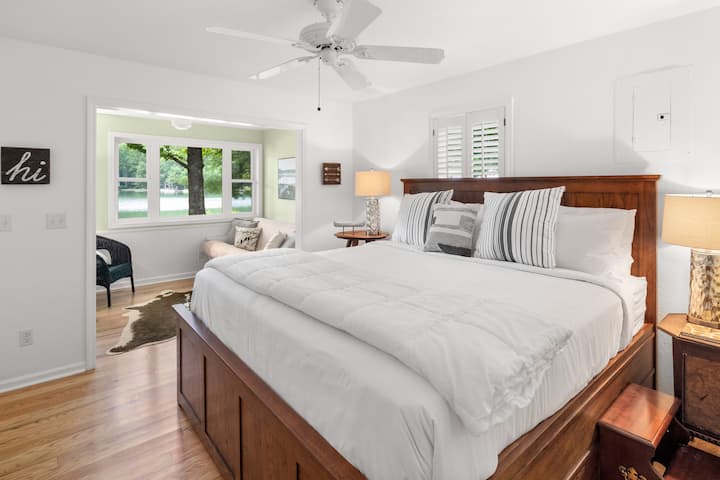 Chumba cha kifahari kilicho na kitanda cha kifahari cha mfalme na eneo la kuketi linalotazama ziwa.