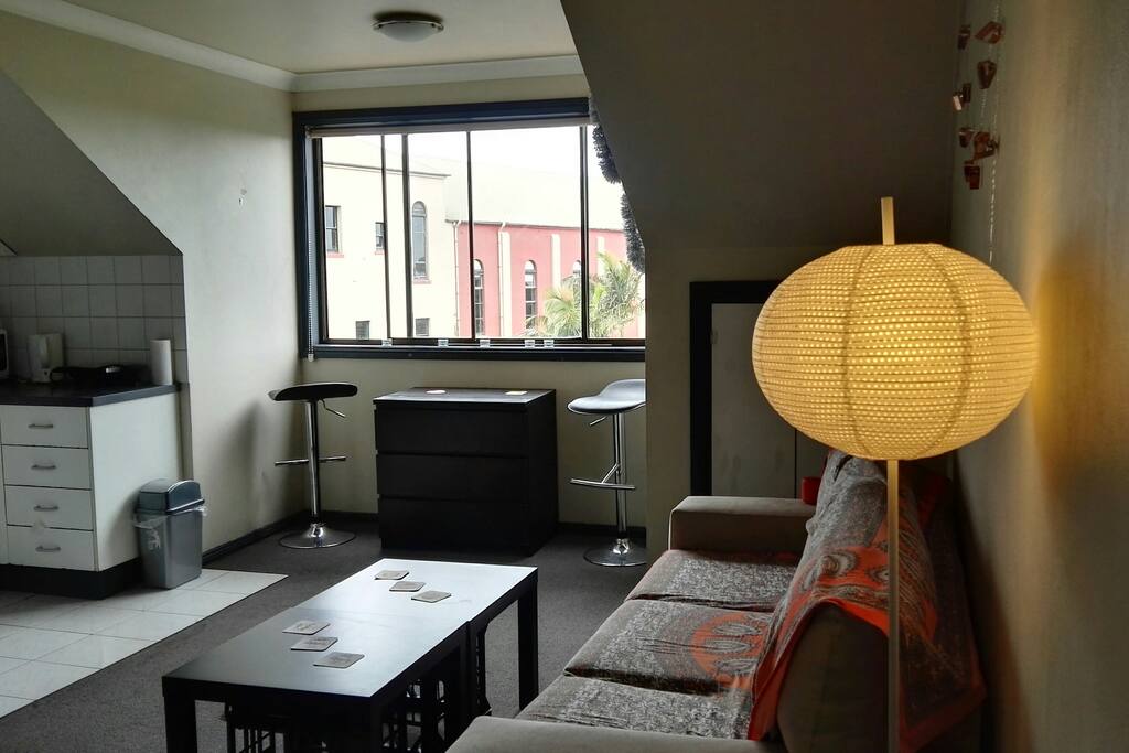 The cozy main room of the apartment, where the kitchen, living-room and a couple of stools invite you to chill out.