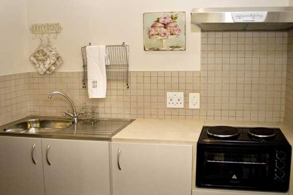 Kitchen with small stove, microwave and fridge.