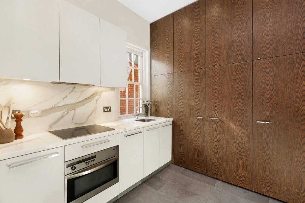 Modern kitchen with convection oven, dishwasher, electric stove, small internal laundry.