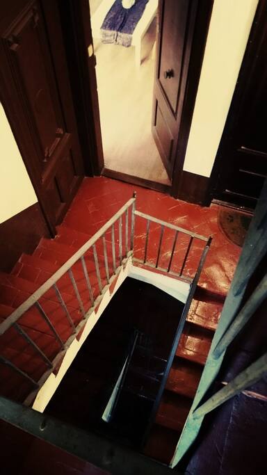 Son las escaleras mostrando la puerta de entrada del apartamento, tomado desde arriba . Es una primera planta real.