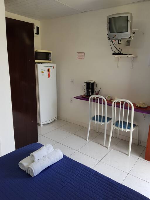 Armário, Geladeira, Microondas, Cafeteira e espaço para refeição.