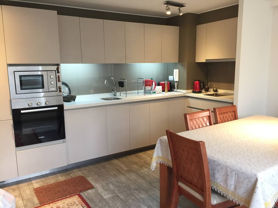 Cocina equipada completa: microondas, horno eléctrico, campana, cocina vitrocerámica, refrigerador, utensilios de cocina.