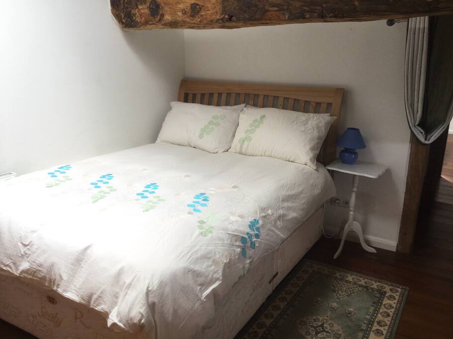 Double bedroom, exposed beams, stone walls, velux windows with blind.