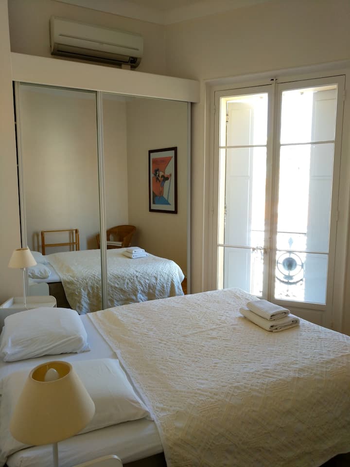 Slaapkamer 3 - Tweepersoonskamer met queensize bed, kastruimte en uitzicht op de Rue Meynadier.