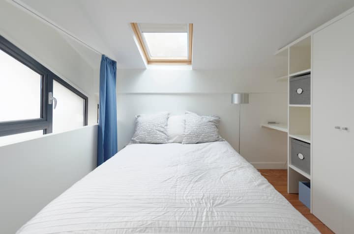 mala spavaća soba na katu s malim radnim stolom i dovoljno prostora za odlaganje