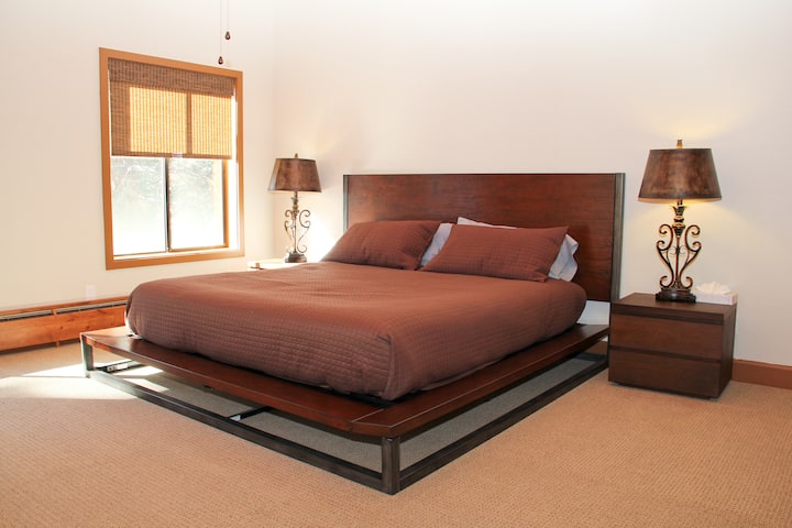 غرفة نوم رئيسية بسرير بمقاس كينج وأسقف بطول 16 قدمًا وحمامها الخاص