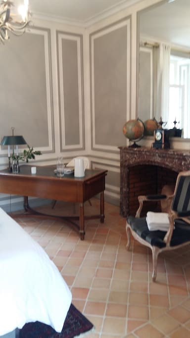 Chambre avec cheminée et bureau offrant un confort chaleureux