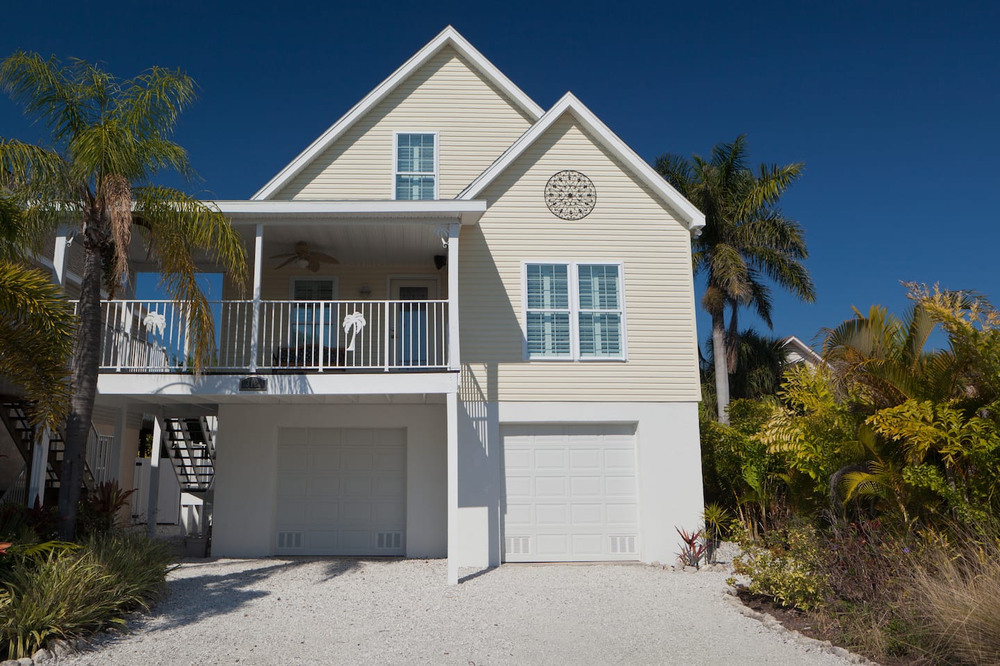 Happy Island Cottage front exterior: two-story coastal home with palms, Holmes Beach