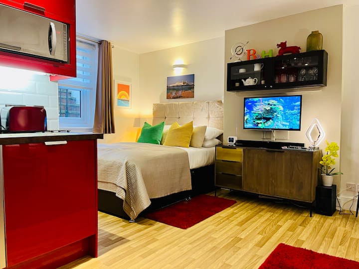 מיטת קינג סייז עם מקום אחסון מתחת עם מצעים באיכות של מלון. מכשיר רדיו עם שעון שיכול לטעון טלפונים ניידים תואמים באופן אלחוטי. 