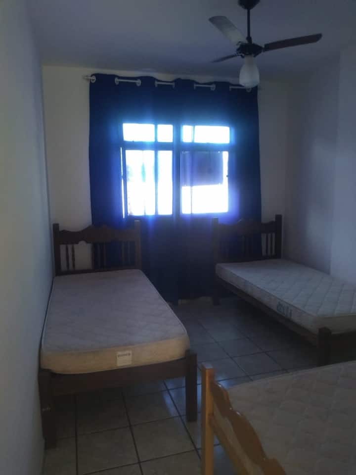 Vitanda vitatu vya mtu mmoja, feni ya dari na skrini kwenye dirisha.
