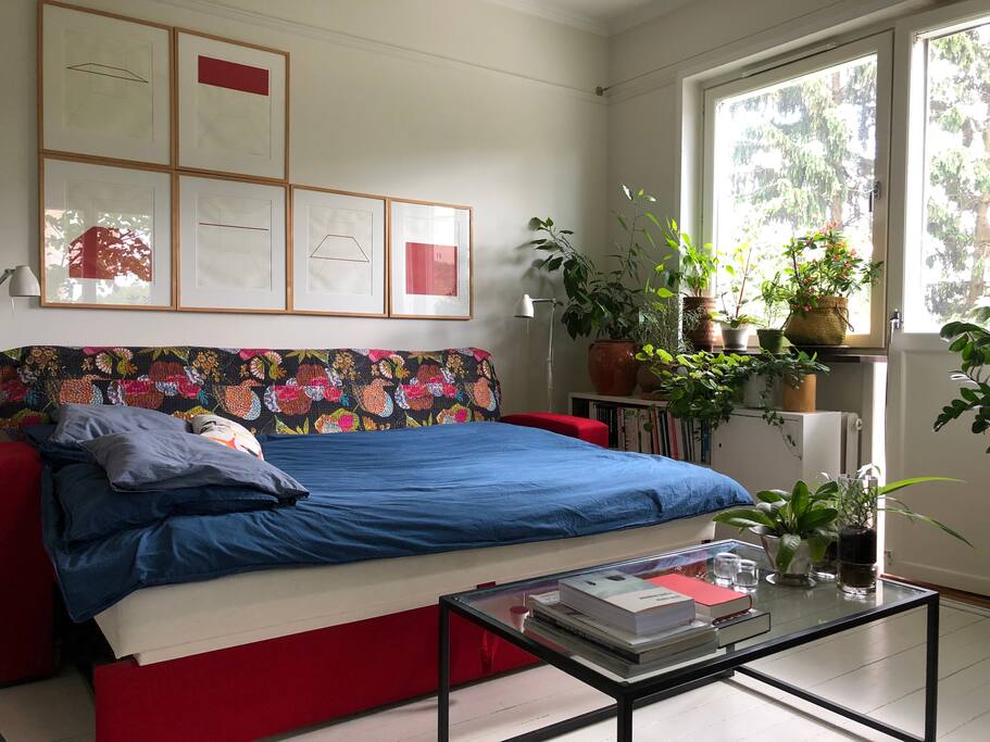Dubble bed in living room with lush garden outside.