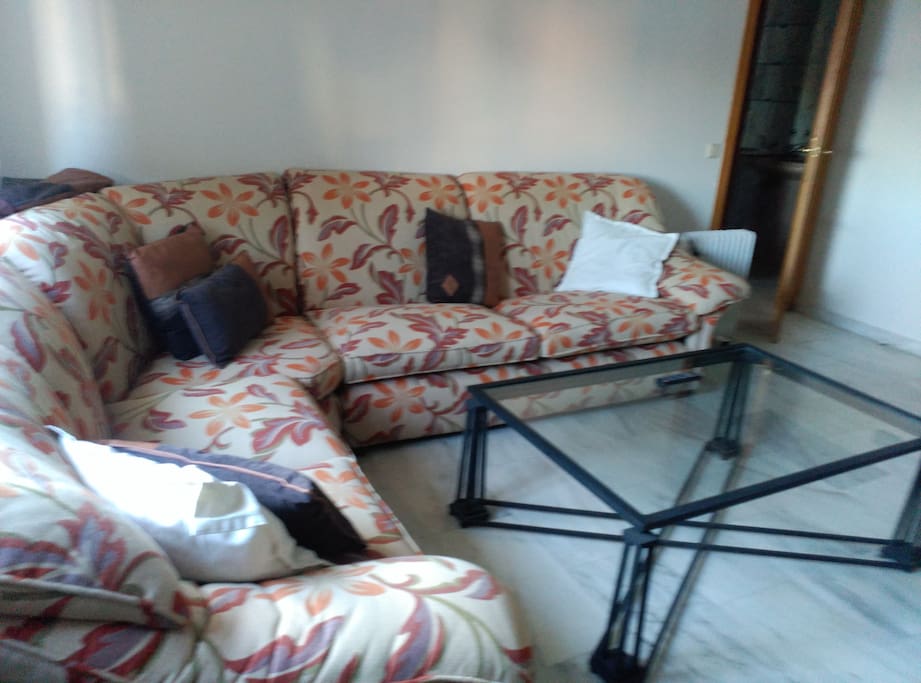 Salon con dos mesas, sillas y sofa rinconera
