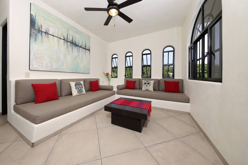 Spacious indoor livingroom with oversized couches large windows and ceiling fans