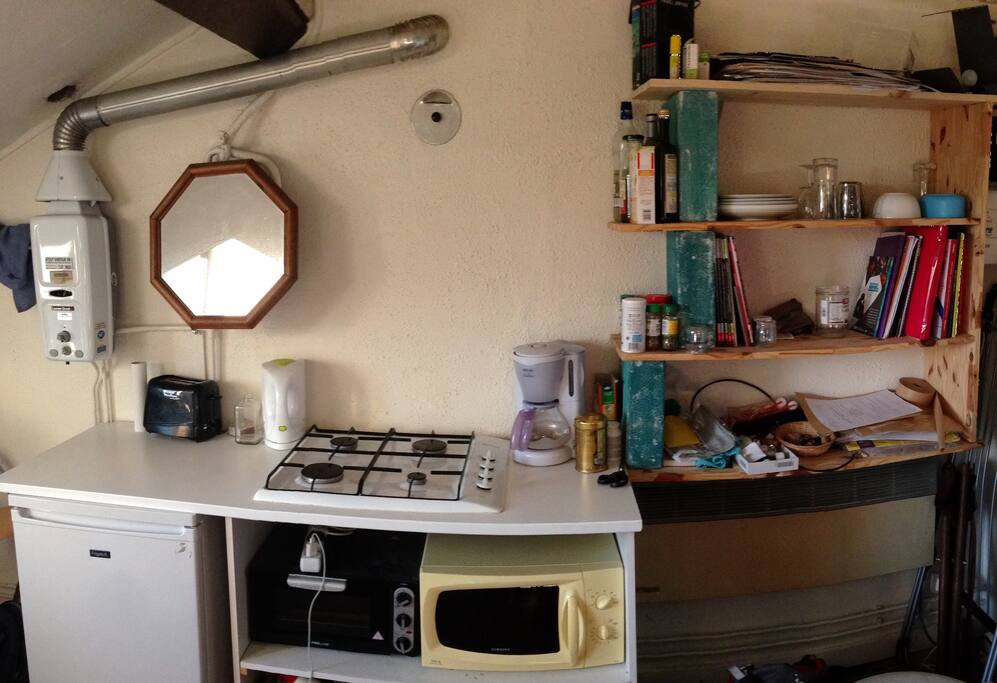 espace de cuisine fonctionnel avec micro-ondes, petit four, plaques de cuisson, cafetière et grille pain.