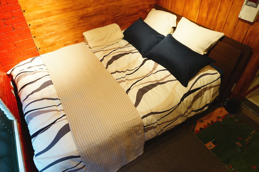 Comfortable double bed is in room.
