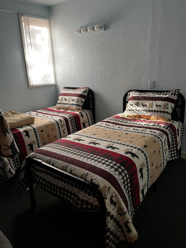 2 kovové samostatné postele v poschodovej izbe s prenosným ohrievačom.