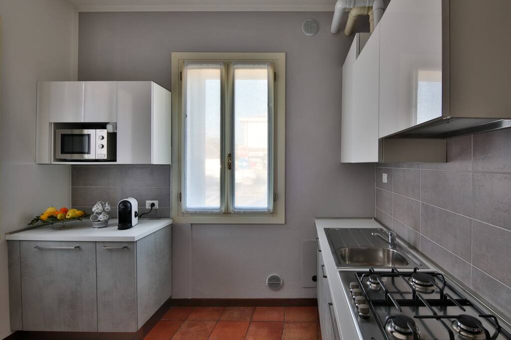 cucina dotata di forno a microonde, piano cottura, stoviglie e macchina del caffé