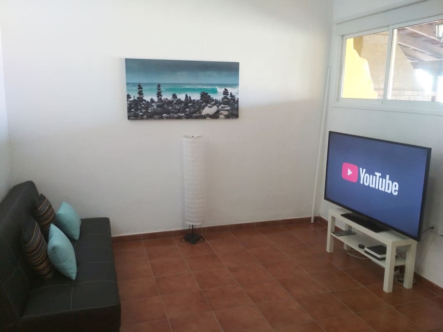 Salón con un sofá cama de cuatro plazas, y smart TV con entrada USB y HDMI e internet (Wi-Fi)